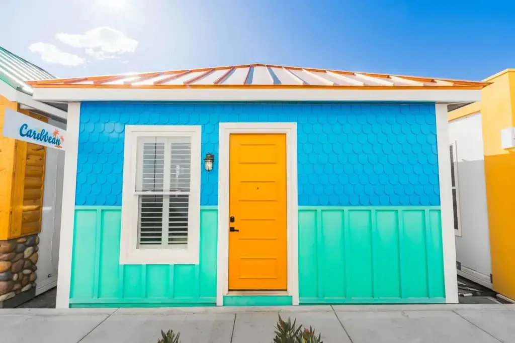 Colorful Boxabl modular home featuring a bright blue exterior with turquoise paneling and a vibrant yellow door, showcasing modern design elements suitable for sustainable living in San Diego.