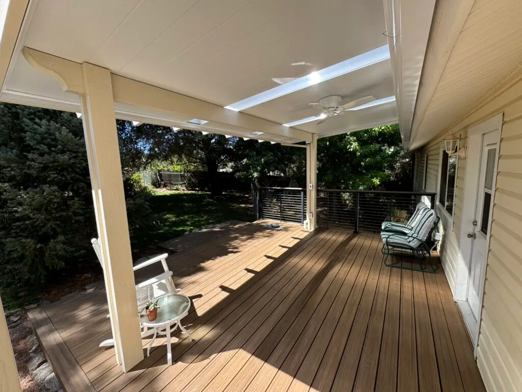 Covered outdoor deck with wooden flooring, ceiling fan, and seating area, showcasing custom design and quality craftsmanship for enhanced outdoor living in coastal environments.