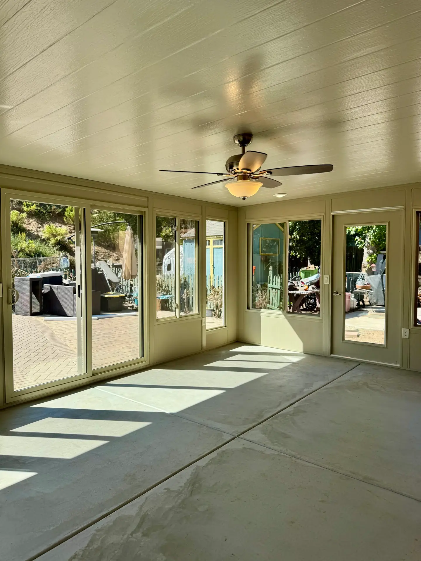 Sunroom interior featuring large glass windows for natural light, ceiling fan, and concrete flooring, designed for energy efficiency and comfort, reflecting Southwest Builders' custom sunroom construction expertise.