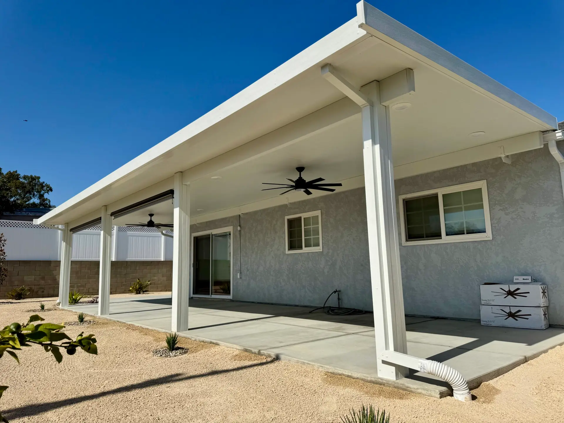 Custom insulated patio cover installation featuring a sleek 12'x40' Elitewood Classic design, with integrated ceiling fans and LED lights, enhancing outdoor living space at a ranch-style home in Lakeside, CA.