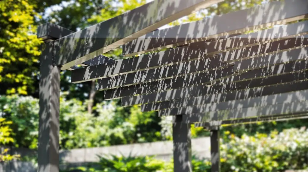 Aluminum pergola structure with slatted roof casting shadows, surrounded by lush greenery, emphasizing low-maintenance outdoor design.