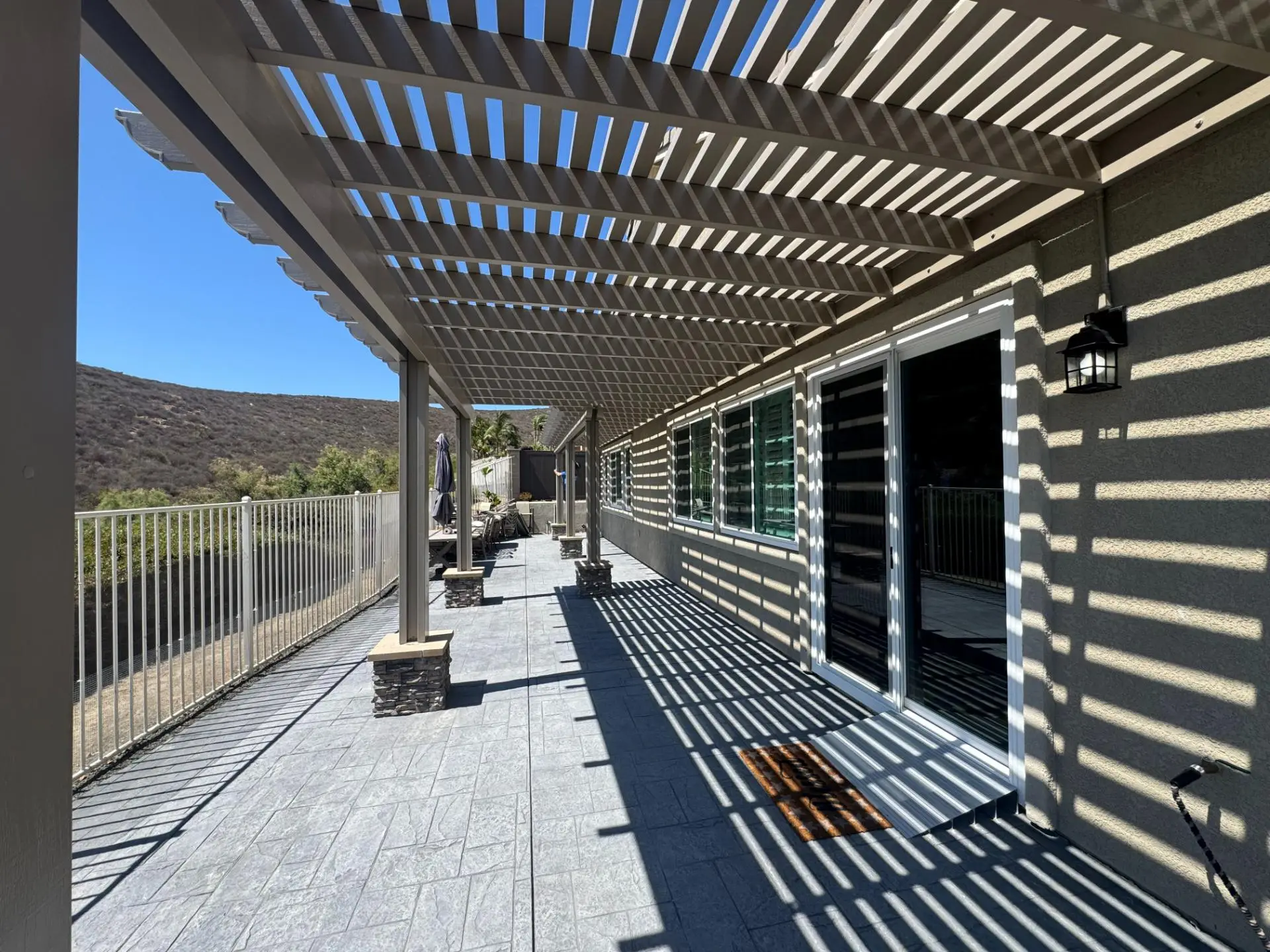Sleek Elitewood Classic Insulated Patio Cover casting shadows on the patio of a ranch-style home in Lakeside, CA, featuring integrated LED lights and a modern design for outdoor comfort.